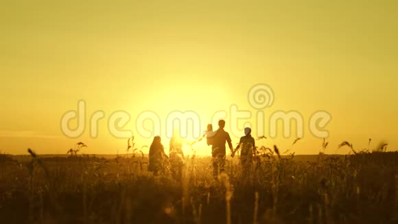 幸福童年的概念幸福的大家庭在夕阳下穿过田野父母和三个孩子走进来视频的预览图