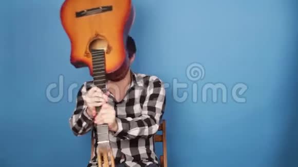 一个疯子用吉他打自己的头那家伙在蓝色背景上把吉他砸在头上视频的预览图