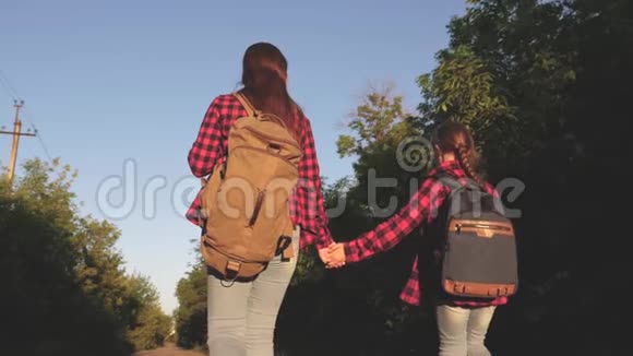 少女旅行牵手徒步旅行者女孩儿童旅行者带背包的女孩在乡间小路上视频的预览图