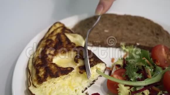 盘子里有美味的早餐面包番茄沙拉和奶酪女孩用叉子的手折断了一块视频的预览图