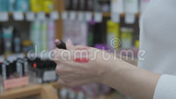 在商店里买化妆品女人在商店里选择彩色化妆品女士使用化妆测试器视频的预览图