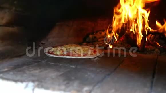 自制和美味的莫扎雷拉奶酪比萨饼在粘土烤箱中煮熟背景中有木头火焰视频的预览图
