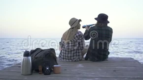 穿着格子衬衫的希普斯特千禧一代游客夫妇看着扔出的望远镜在大海的背景下聊天视频的预览图