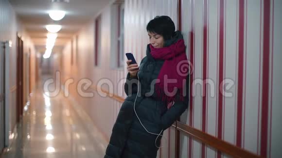 一个穿着红领巾和黑色衣服的女孩站在酒店里使用智能手机视频的预览图