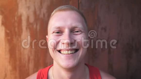 靠近微笑的男人金发站在模糊的大门背景上快乐年轻运动员的肖像视频的预览图