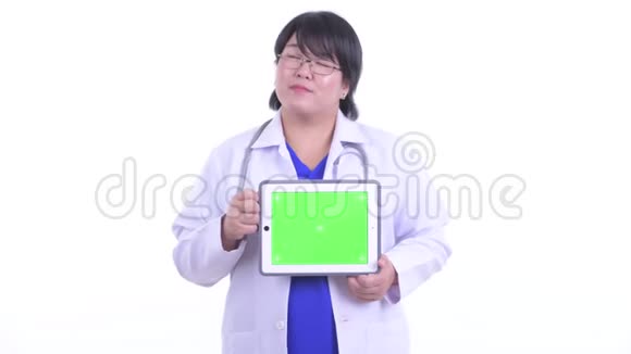 快乐超重的亚洲女医生在看数字平板电脑视频的预览图