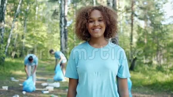 穿着志愿者制服的快乐非裔美国女孩在被污染的森林中的肖像视频的预览图