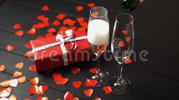 在礼品盒附近的一张黑色桌子上香槟被装进一个玻璃杯里视频的预览图
