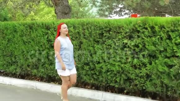 一个红头发的女人沿着绿地散步视频的预览图