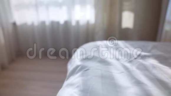 舒适的白色床配有凌乱的亚麻布和日光灯视频的预览图