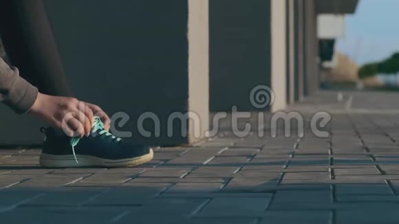 穿着运动鞋系鞋带的女孩在城市街头慢跑视频的预览图