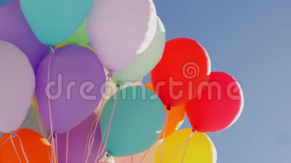 许多彩色气球在蓝天背景下飞行在透明的蓝天上飞舞着五颜六色的空气球视频的预览图