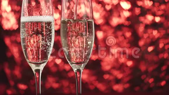 香槟被倒入一个红色背景上的玻璃杯中里面有许多心靠近视频的预览图