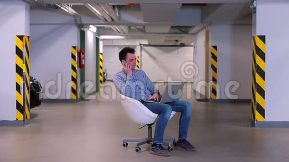 一名上班族坐在地下车库的椅子上手提电脑视频的预览图