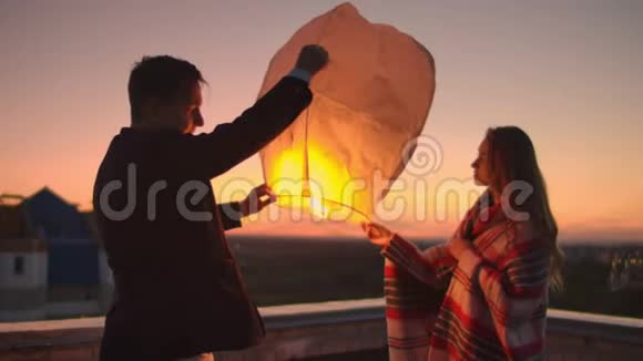晚上在屋顶上发射一个天灯恋人们在一起中国天灯视频的预览图