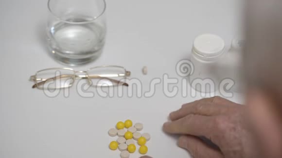 退休人员在餐桌特写时清点白色和黄色药物视频的预览图