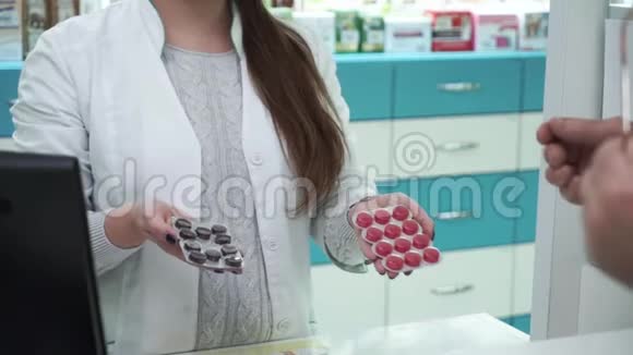 无法辨认的女性药剂师向顾客提出两种变体的药物男性购买者选择视频的预览图