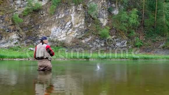 飞钓在山河有长发和圣诞老人胡须的成年人拿着钓鱼竿巴的娱乐和体育活动视频的预览图