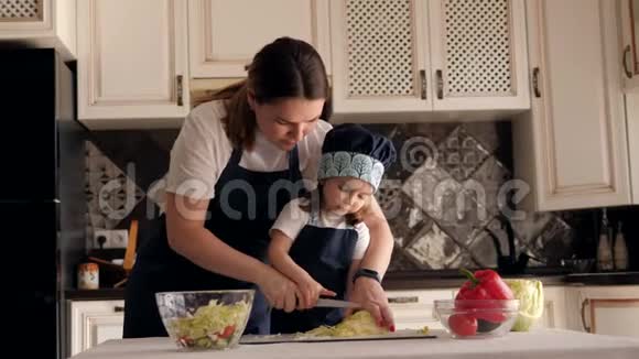 母亲和小女儿穿着围裙在剪板上剪甘蓝视频的预览图