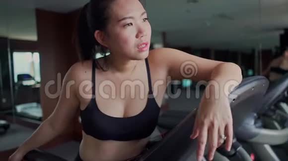 年轻的美丽的汗流浃背疲惫的亚洲跑步运动员在慢跑锻炼后在健身房跑步机上呼吸疲惫视频的预览图