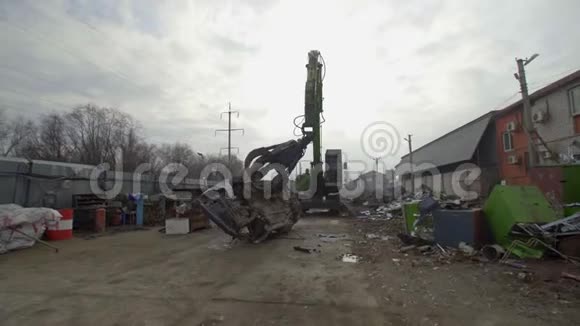 机械臂从城市垃圾填埋场的一堆旧车上抓取的机器视频的预览图