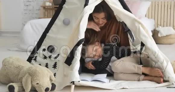 母亲和儿子正在一起读一本书男孩躺在女人腿上视频的预览图
