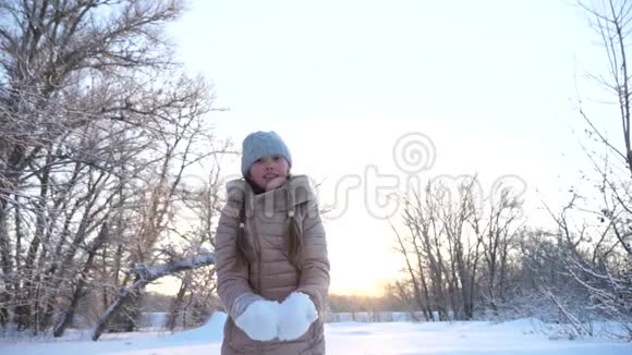 快乐的童年概念在冬天的公园里孩子们把雪花扔到顶端感到高兴和微笑慢动作女孩视频的预览图