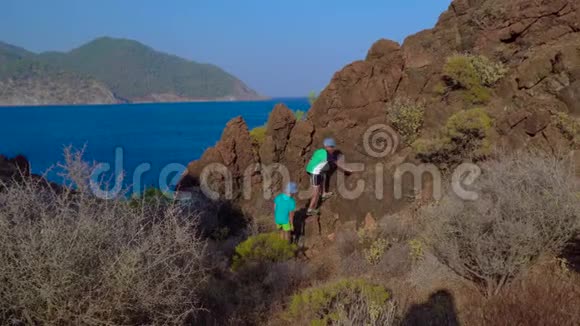孩子们爬上地中海海岸的岩石视频的预览图