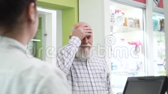 一个长着胡子头痛的老人来到药房年轻的女药剂师为顾客提供药丸视频的预览图