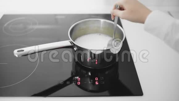 牛奶在平底锅里沸腾女人用平底锅搅拌牛奶视频的预览图