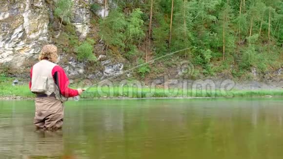 一个钓竿的渔夫站在河里圣诞老人老人乘飞机钓鱼运动山地户外娱乐视频的预览图