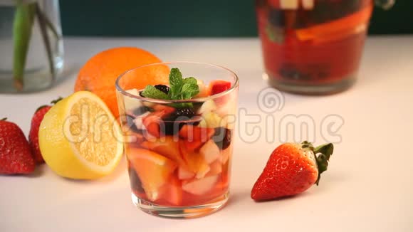 女人的手把一杯红酒新鲜的桑格里亚酒或一杯水果和浆果放在桌子上视频的预览图