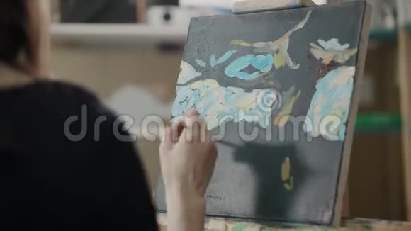 女艺术家在画室里用画笔在画布上作画具有高度的艺术性视频的预览图