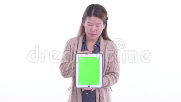 快乐的年轻亚洲女人展示数字平板电脑看上去很惊讶地准备过冬视频的预览图