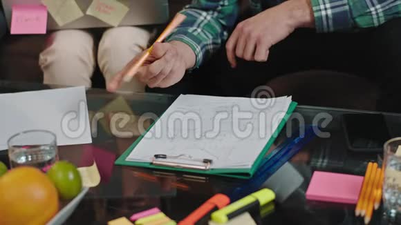 在图书馆里一个学生在做笔记的同时在桌上的论文上做一个项目视频的预览图