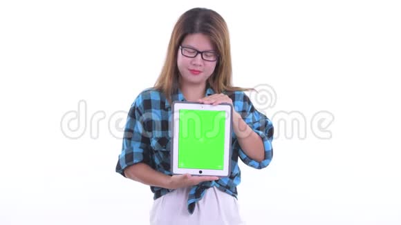 快乐年轻的亚洲潮女一边思考一边展示数码平板电脑视频的预览图