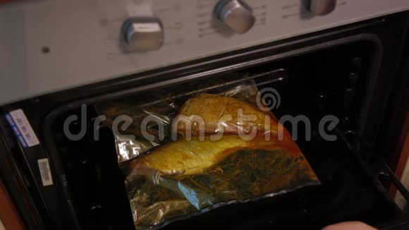 在烤包里用腌料煮整条烤鱼女厨师把一张烤盘和生鱼放入热烤箱食物视频的预览图