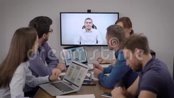 男人和女人都在手机应用开发公司的办公室里通过视频电话听老板说话视频的预览图