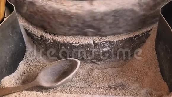 特写镜头在中世纪手工驱动的磨石磨小麦的老磨石上磨粒的过程这就是视频的预览图