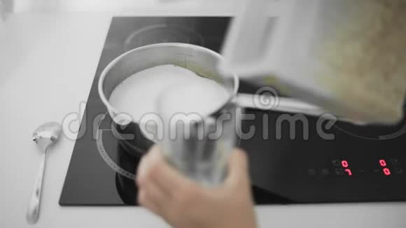 厨房灶台上的金属平底锅内有煮牛奶的燕麦片视频的预览图
