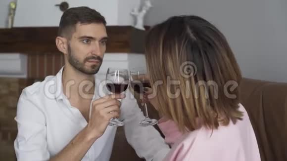年轻漂亮的白种人和他的妻子坐在家里喝红酒在肩膀上射击已婚夫妇视频的预览图