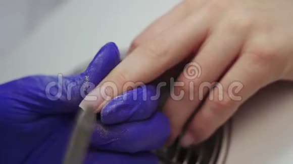 在一家沙龙里接受美甲的女性美容师带着指甲档案接受指甲修剪的女人美容师档案视频的预览图