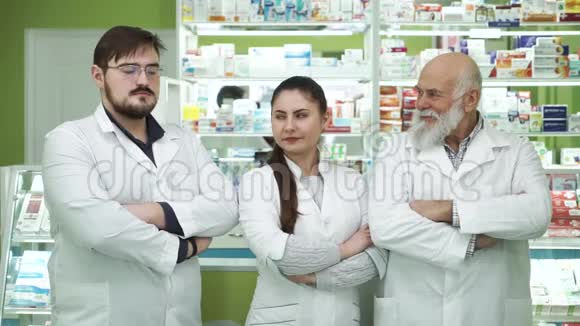 三个不同年龄的白种人药剂师互相看着对方对着镜头微笑高度专业视频的预览图