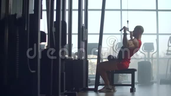 健身男子在健身房锻炼拉倒机年轻的健身者在健身房锻炼拉床视频的预览图