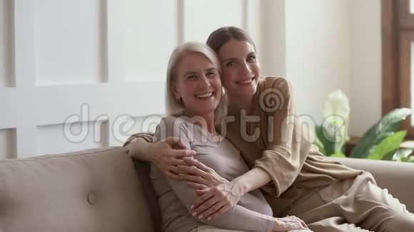 积极成熟的母亲和年轻的女儿笑着拥抱在一起肖像画视频的预览图