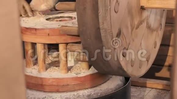 米勒把谷物放在一块旋转的古昆石里带颗粒的机械手动磨机那人把谷物磨成视频的预览图