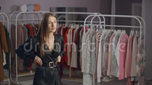 穿着黑色连衣裙的漂亮女孩在商店里照镜子穿着晚礼服视频的预览图