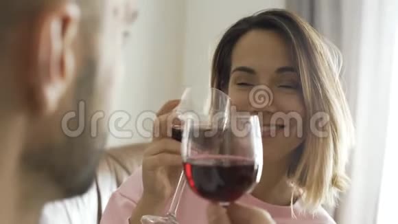 可爱的年轻白种人男人和他的妻子坐在家里喝红酒在肩膀上射击已婚夫妇视频的预览图