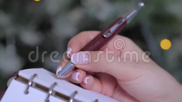 女人手拿笔写着在老式笔记本电脑组织者做清单视频的预览图