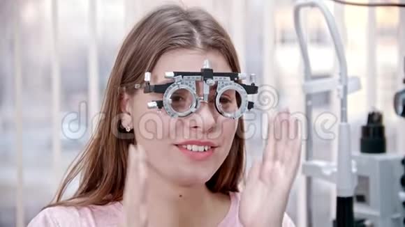 眼科治疗一位年轻的微笑妇女坐在视力测试的验光装置中读一些东西视频的预览图